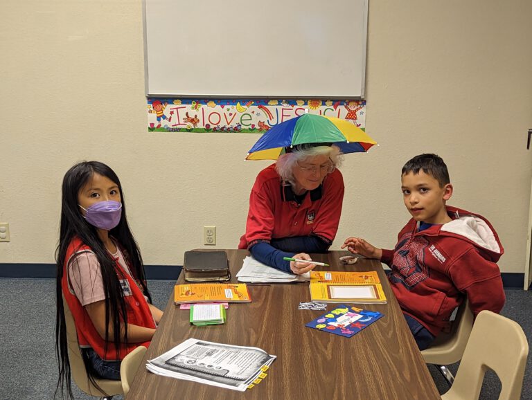 An Awana leader going through handbook pages with two clubbers