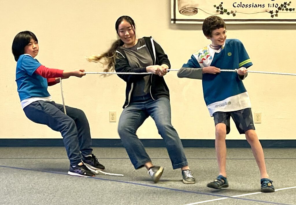 Three Awana clubbers playing tug-of-war in the church gym