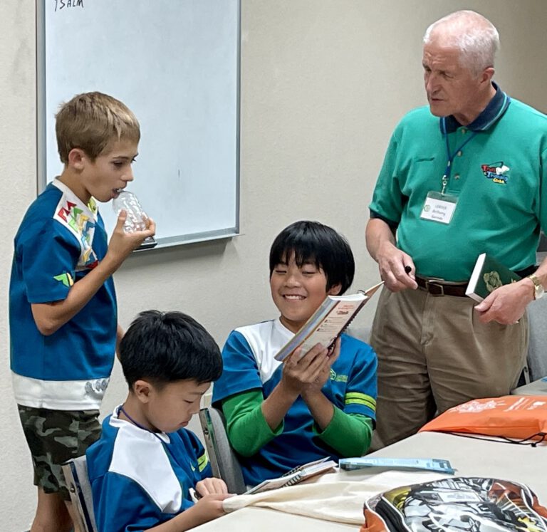 Clubbers reading their Awana handbooks while a leader listens