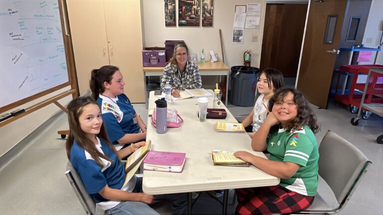 Students and a leader talking around a table with their handbooks